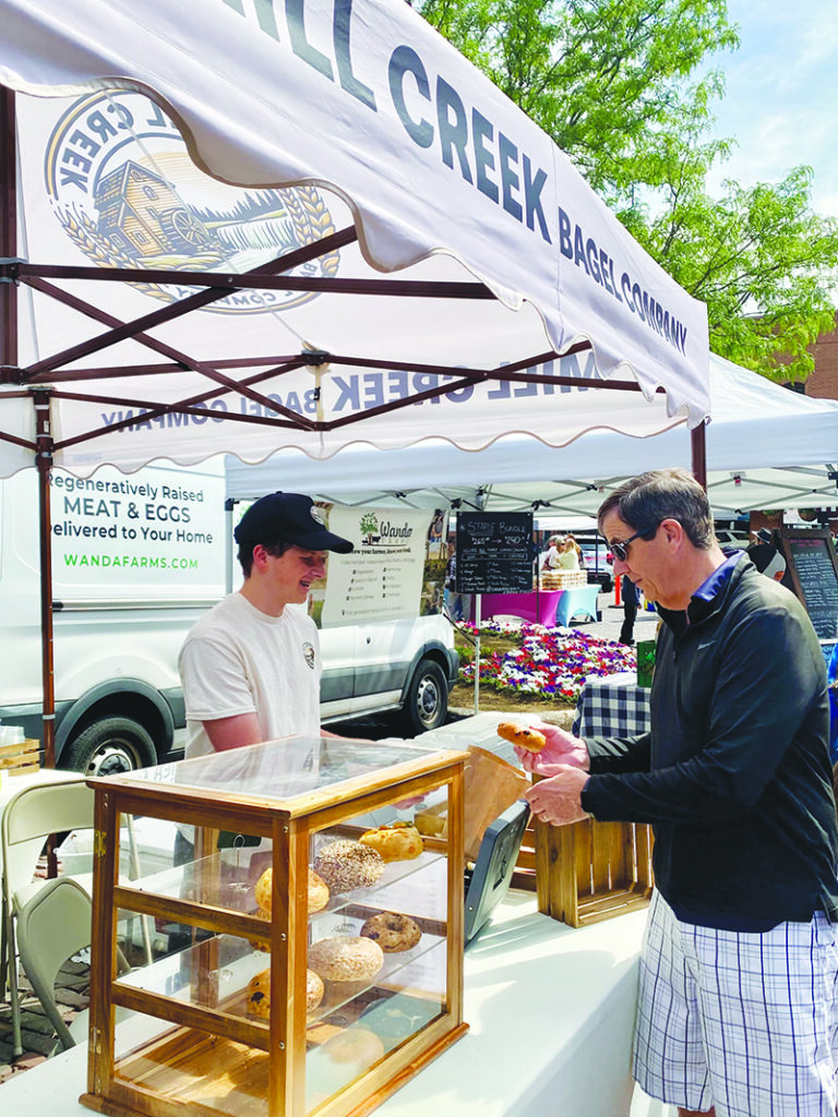 Independent photo by Susan W. Murray.
David Morphew of Woodstock takes his bagel from Jake Anderson, market manager at the Mill Creek Bagel Co.